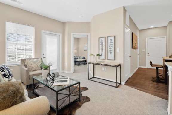 A living room with a glass coffee table and a brown furry chair.
