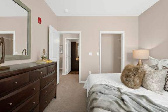 A bedroom with a bed, dresser, and mirror.