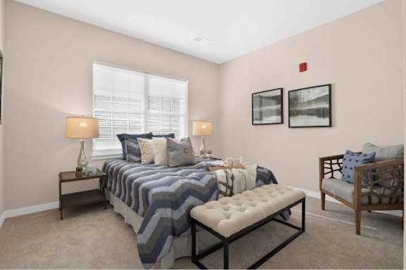A bedroom with a bed, a bench, and two lamps.