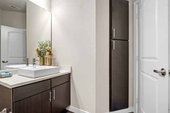 a bathroom with dark cabinets and a white sink