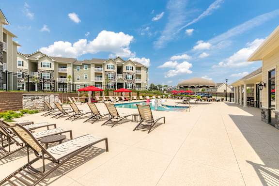 A sunny day at the poolside with chairs and umbrellas.