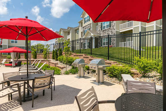 A patio with a table and chairs under a red umbrella.