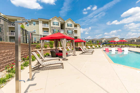 A pool area with a red canopy and lounge chairs.