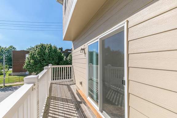 A balcony with a sliding glass door and a white railing.