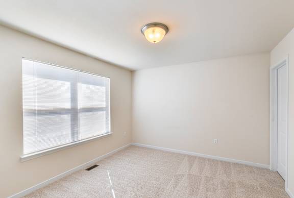 A room with a window and carpeted floor.