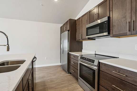 A kitchen with a stainless steel refrigerator, oven, and microwave.