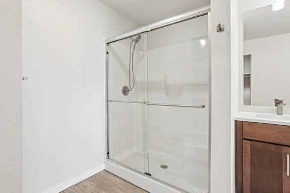 A white bathroom with a walk-in shower and a white sink.