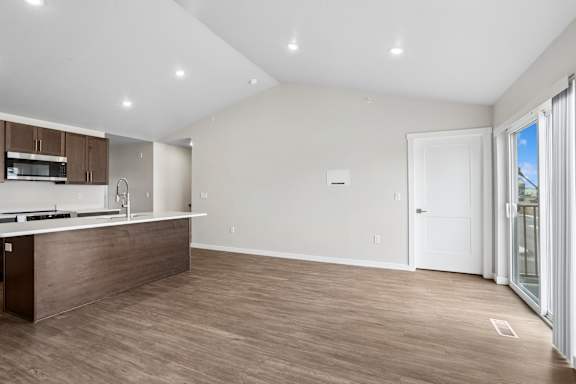 A kitchen with a white countertop and wooden flooring.