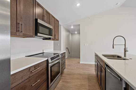 A modern kitchen with dark wood cabinets and stainless steel appliances.