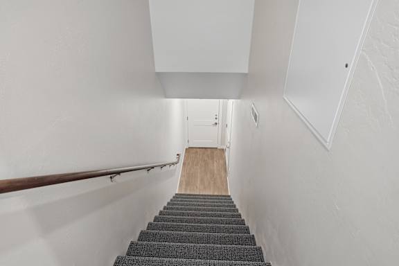 A stairway with a wooden floor and a metal handrail.