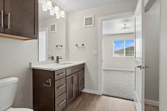 A bathroom with a white tub and a white sink with brown cabinets.