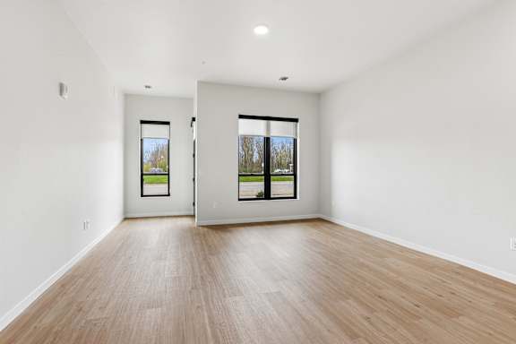 A room with two windows and wooden flooring.