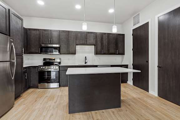 A modern kitchen with dark wood cabinets and a white island.
