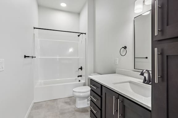 A white bathroom with a toilet, sink, and shower.