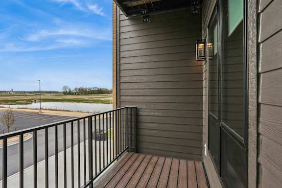A balcony with a black railing and a wooden floor.