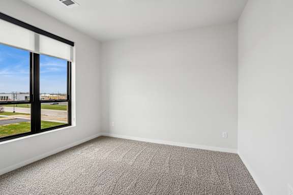 A room with a carpeted floor and a large window overlooking a street.