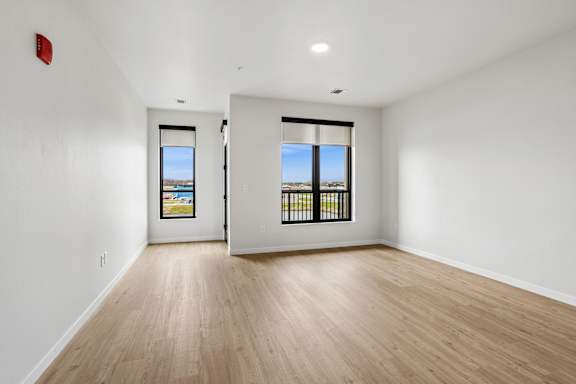 A room with two windows and a fire extinguisher on the wall.