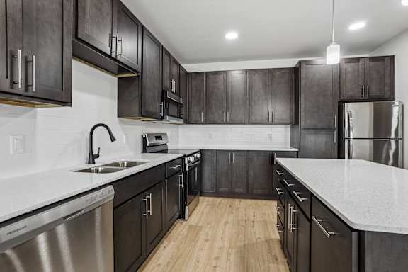 A modern kitchen with dark wood cabinets and stainless steel appliances.