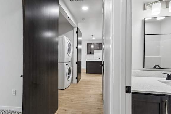 A modern bathroom with a wooden door and a white sink.