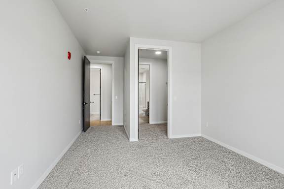 A hallway with a carpeted floor and white walls.