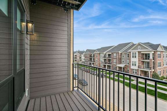 A balcony with a black railing and a view of apartment buildings.