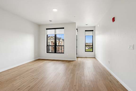 A room with a wooden floor and a window showing a view of a house.