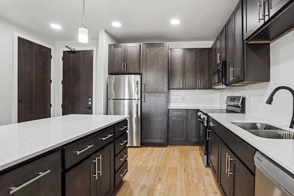 A modern kitchen with dark wood cabinets and stainless steel appliances.