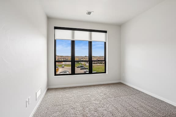 A room with a large window overlooking a parking lot.