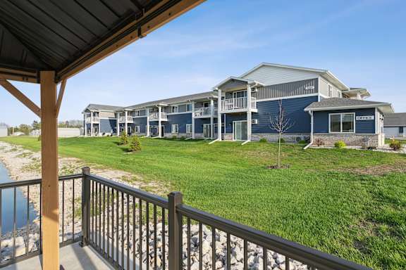 A view of a building with a balcony overlooking a grassy area and a body of water.