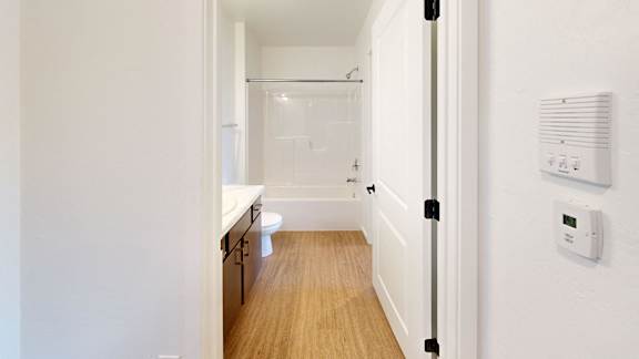 A white door is open to a small bathroom with a toilet and sink.