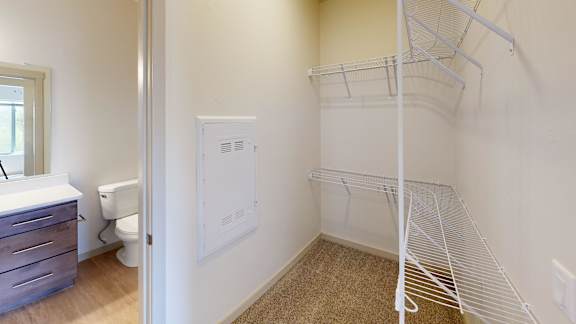 A white closet with a shelf and a white door.