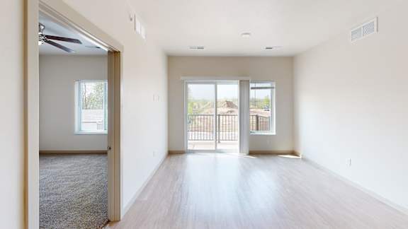 A spacious room with a sliding glass door leading to a balcony.