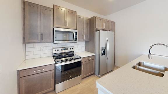 A kitchen with a stove, oven, microwave, and refrigerator.
