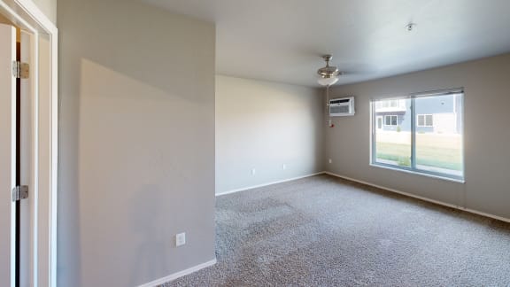 an empty living room with a large window and white walls