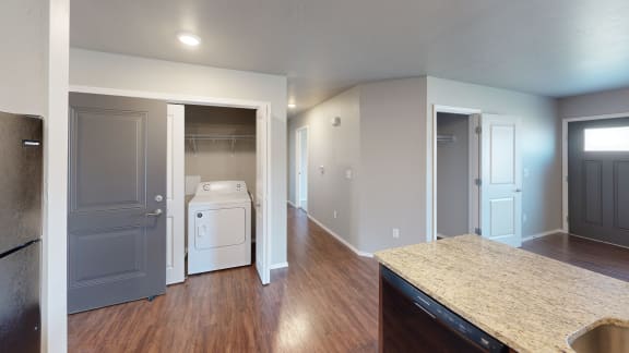 a kitchen with a washer and dryer and a door into a laundry room