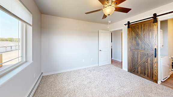 A room with a ceiling fan and a sliding door.
