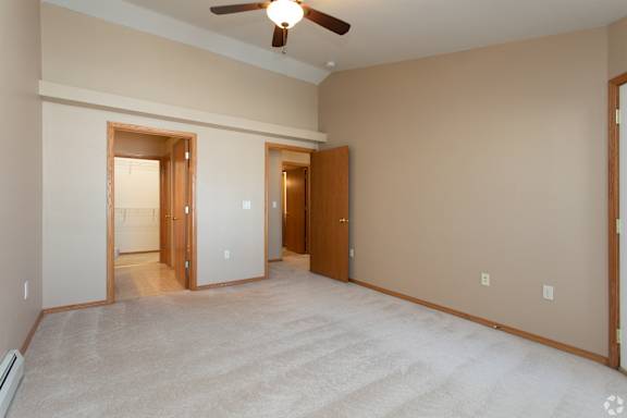 A room with a ceiling fan and carpeted floor.