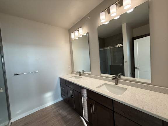 A bathroom with a sink, mirror, and a shower.