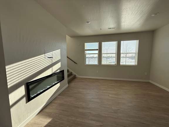 A room with a wooden floor and a window with blinds.