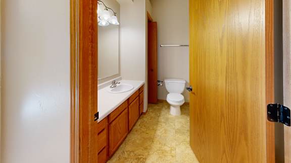 A bathroom with a toilet, sink, and mirror.