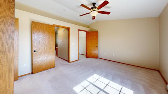 A room with a ceiling fan and a window letting in sunlight.