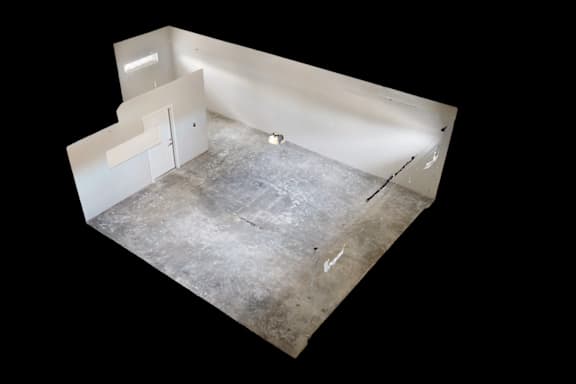 A white room with a concrete floor and a white wall.