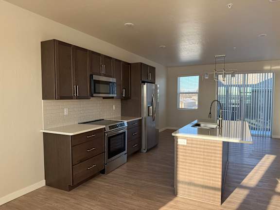 A modern kitchen with dark brown cabinets and stainless steel appliances.