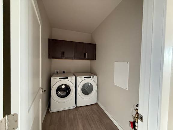 A laundry room with two washing machines and a cabinet above them.