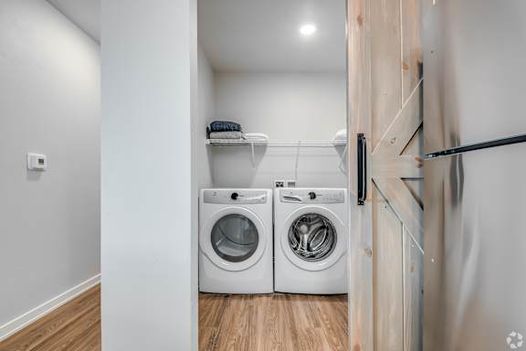 A laundry room with two washing machines and a shelf above them.