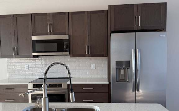 A kitchen with a stainless steel refrigerator and brown cabinets.