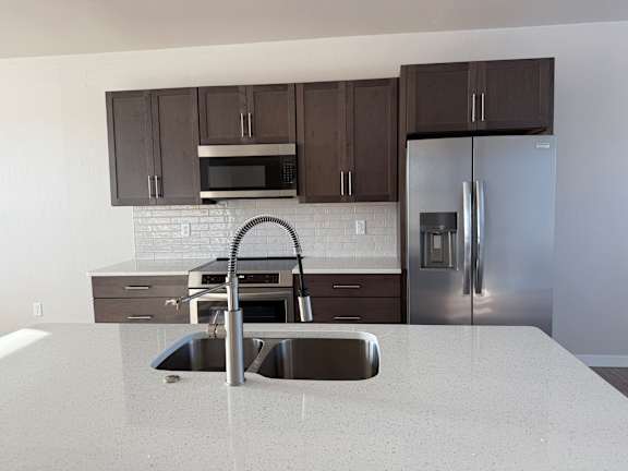 A kitchen with a sink and a refrigerator.
