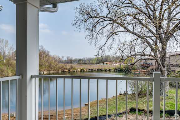A view from a balcony overlooking a body of water with a leafless tree in the foreground.