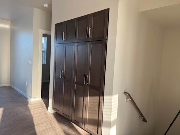 A large, dark brown wardrobe with a mirrored door is in a room with light wood flooring.