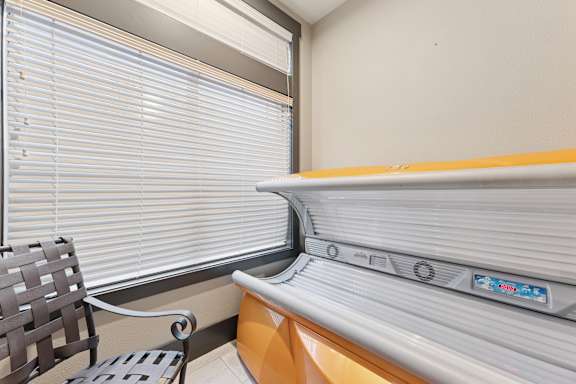 A room with a window covered by blinds and a bench with a backrest.